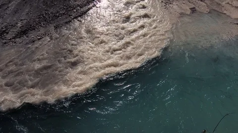Slow motion looking down brown and clean green water mixing together in river Video stock 121513330