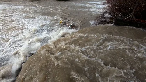 Slow motion looking down dirty rainfall water flows in small concrete channel Stock Footage 120354379