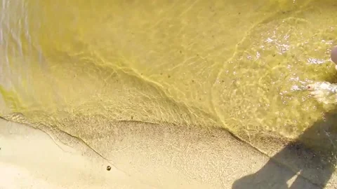 SLOW MOTION: Looking at your bare feet as you walk along a sandy beach washed by Stock Footage 159176737