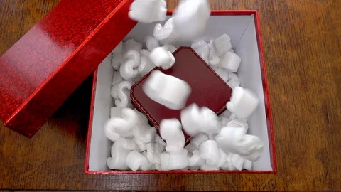Slow motion - Loose fill packaging falling into presentation box to be shipped. Video stock 106975396
