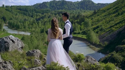 Slow motion. A loving couple is standing on top of a mountain. A gentle kiss of  Stock Footage 92720002