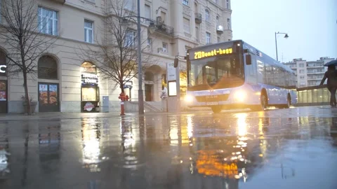 Slow motion low angle shot of bus passing in melancholic, gloomy, rainy morning Vídeo Stock 195960649