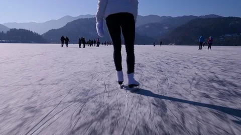 Slow motion - Low angle view of happy woman ice skating on frozen lake Bled Vidéo 81468157