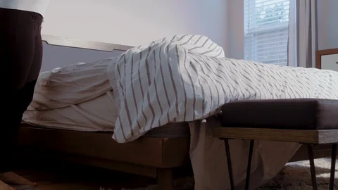 Slow motion low angle view of a person fixing the bed, lifting and airing Vidéo 103834310
