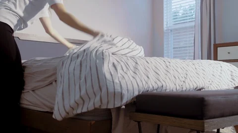 Slow motion low angle view of a person fixing the bed, lifting and airing Vidéo 103834337