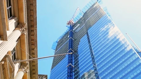 Slow motion low angle view on construction crane by skyscraper tower in London Stock Footage 108604026