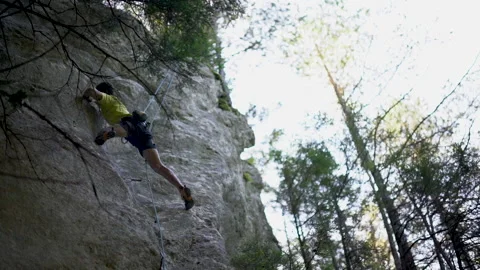 Slow motion, low angle of young male rock climber searching, reaching and 스톡 동영상 131838923