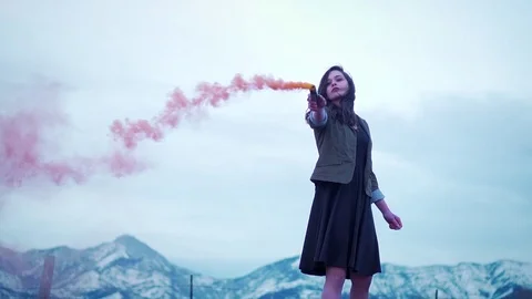 Slow motion low shot of brunette woman models with smoke in front of mountains Stock Footage 73125044
