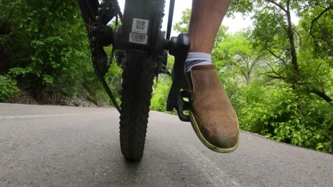 Slow motion low shot of a man riding bike path in forest with family Video stock 137643352