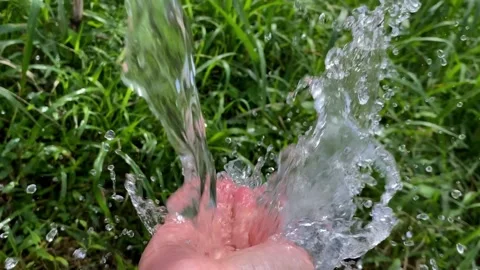 Slow motion macro of clear pure water stream flowing into hand with splash Stock Footage 276358100