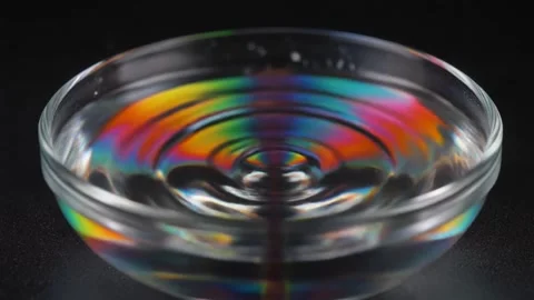 Slow-motion macro of colored water rippling inside a glass bowl as deep bas.. Stock Footage 324516013