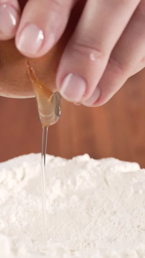 Slow-motion macro of female hands holding an egg and dropping it into flour.. Stock Footage 312169729
