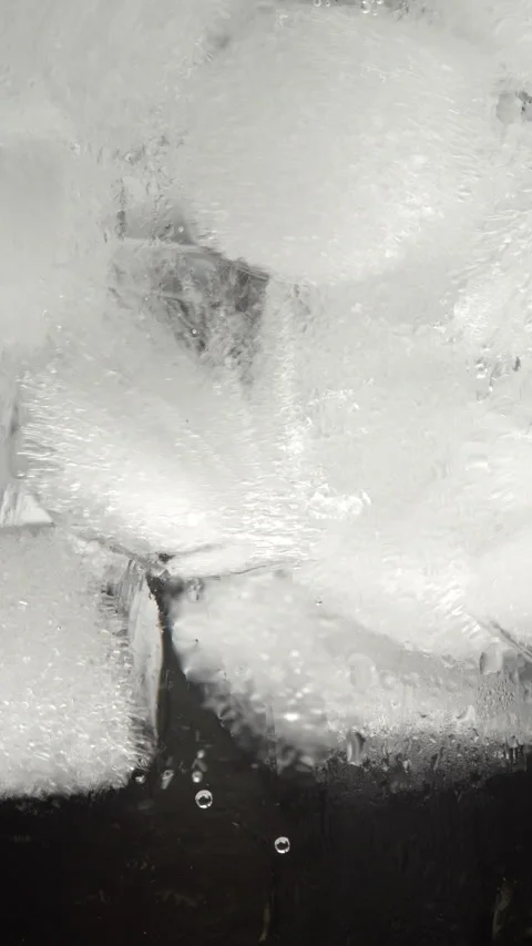 Slow motion macro footage of ice cubes inside frosty glass with condensatio.. Stockbeeldmateriaal 336661268
