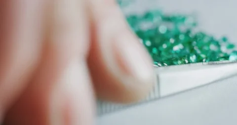 Slow motion macro of goldsmith sorting high quality green diamonds. Video stock 114942927