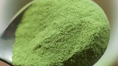 Slow motion macro of an iron spoon with handful matcha being poured into cup Stock Footage 159582106