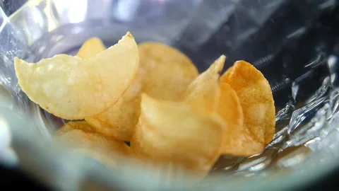 Slow motion macro shot of chips falling down into glass bowl Stock Footage