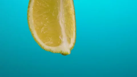 Slow Motion Macro Shot of Flowing Lime Juice from Lime Slice. Blue background Stock Footage 202009453