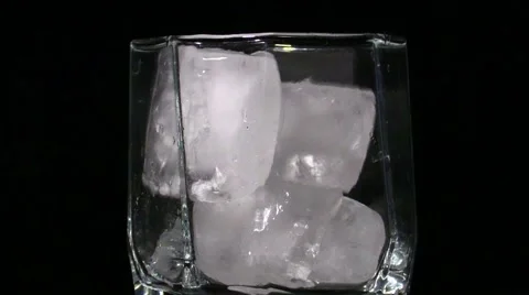 Slow motion macro shot of ice cubes falling into a cocktail glass Stock Footage 51652641