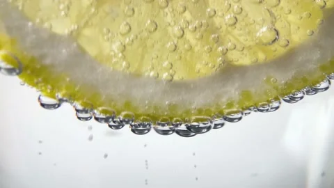 Slow Motion Macro shot of a lemon slice in water bubbles, Soft Drink with Ice Stock Footage 234453754