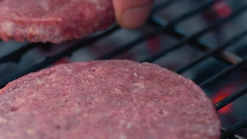 Slow motion macro shot: Man places burger on grill next to sizzling patty Stock Footage 101264490