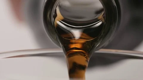 SLOW MOTION: Macro shot of pouring of a brown beverage from a glass bottle Video stock 71568727