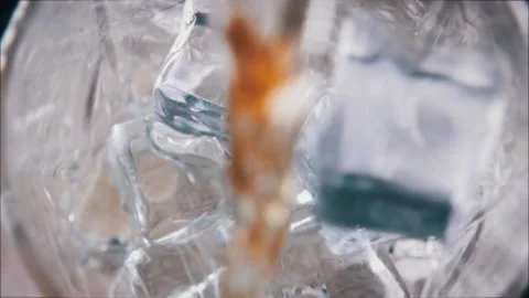 Slow Motion Macro Shot of Pouring Whiskey into Glass with Ice Stock Footage 138982045