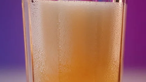 Slow motion macro shot of pouring bright yellow beer from bottle into a glass Stock Footage 245983822