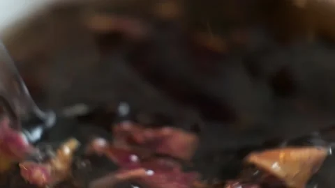Slow motion macro shot of stirring tea leaves in a cup with an iron spoon Stock Footage 159582236