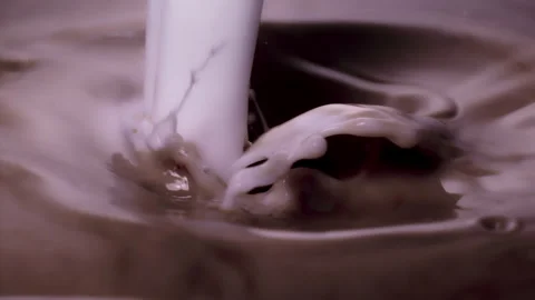 Slow motion, macro shot: White milk pouring into brown, chocolate milk. UHD25p Stock Footage 249590089