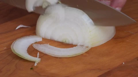 Slow Motion Macro Slice of a White Onion on a Wooden Cutting Board Stock Footage 317771741
