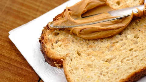 Slow motion macro of spreading creamy peanut butter on low-carb toast Stock Footage