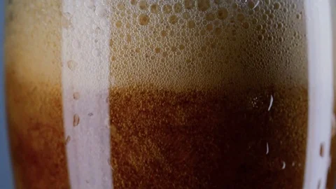 Slow motion macro still life of foamed dark beer poured in transparent glass Stock Footage 78484603