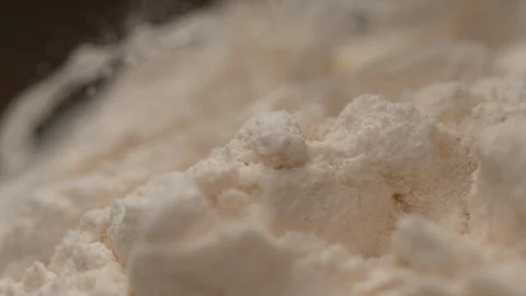 SLOW MOTION, MACRO: Transparent liquid flowing down a heap of flour in a bakery. Stock Footage 103256258