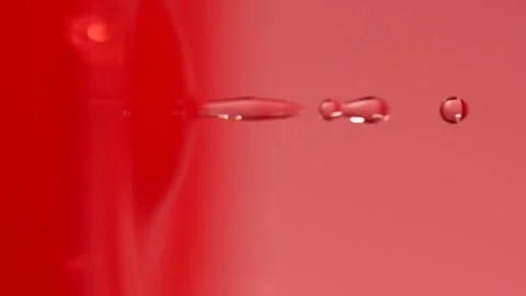 Slow motion of macro water drop falling into pink water, closeup droplet splash Stock Footage 198302602