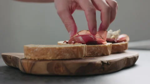 Slow motion man add pancetta to slice of ciabatta with fig marmalade Stock Footage 292396726