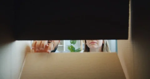 Slow motion of man and woman opening box looking inside smiling having fun Stock Footage