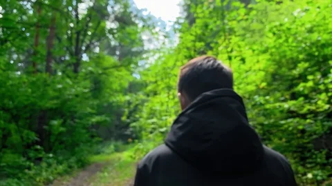 Slow motion . Man in a black jacket walking  in the woods on a sunny day. Stock Footage 113094978