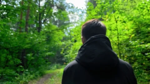 Slow motion . Man in a black jacket walking  in the woods on a sunny day.  Stock Footage 113095146
