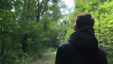 Slow motion . Man in a black jacket walking  in the woods on a sunny day. Stock Footage 113111431