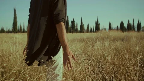 Slow Motion! A man in a black jacket is walking on a field and dry grass Stock Footage 117544767