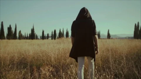 Slow Motion! A man in a black jacket is walking on a field and dry grass Stock Footage 117544856