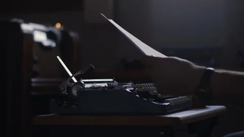Slow motion of a man blowing a candle out next to a typewriter in a moody office Stock Footage 97857192