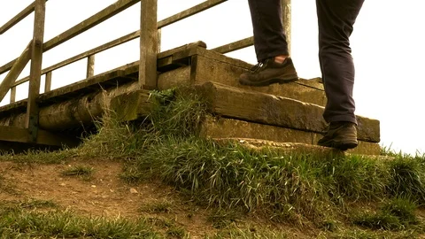 Slow motion – Man climbing steps and crossing an old wooden bridge (rear view). Vídeos de archivo 104972276