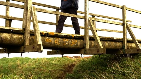 Slow motion – Man crossing an old wooden bridge (side front view). Video stock 104971076
