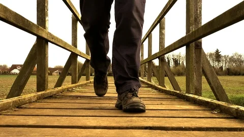 Slow motion – Man crossing an old wooden bridge (front view). Video stock 104971529