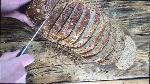 Slow motion. Man cuts bread into slices on wooden cutting board Video stock 123350868