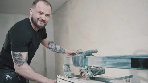 Slow motion of a man cutting tile with precision in a well-lit indoor space Stock-Footage 307040393