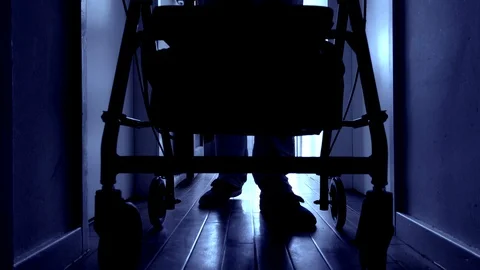 Slow motion - Man entering dark corridor pushing rollator / adult stroller. Vídeos de archivo 108771760