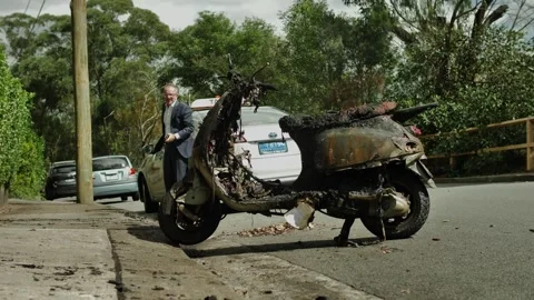 Slow motion man getting out of taxi looks at a burnt scooter dolly 4K Stock Footage 240363835