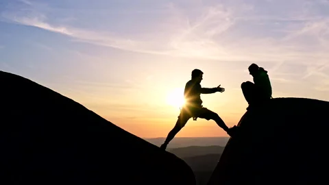 Slow motion of a man gives a hand to a woman helping her down a cliff face. Stock Footage 153961741